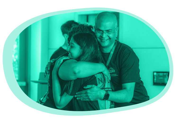 Participants hug; image is tinted turquoise, one of Mizzen Education’s primary brand colors.